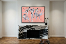 Load image into Gallery viewer, Cupids and Models: Fancy Dress Party...by IsaLu Ishii – framed abstract art print featuring naughty cupids on a pink background, displayed above a black and white marble fireplace mantel in a modern room setting.